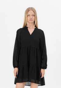 Crna haljina od lagane tkanine, s V-izrezom, dugim rukavima i slojevitim volanima na rubu. Jednostavan i elegantan dizajn.