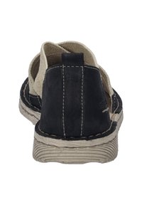 Schwarzer Wildleder-Slipper mit beigen Canvas-Akzenten, sichtbaren Nähten und einer strukturierten Gummisohle, mit offenen Seiten für Atmungsaktivität.