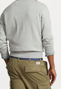 Grå sweatshirt med ribbade muddar och halsringning, matchad med olivgröna cargo-byxor med flera fickor och ett bälte med blå accenter.