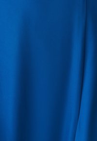 Helles blaues Material mit einer glatten, matten Textur; keine Muster oder Hardware sichtbar. Der Stoff wirkt leicht und weich.