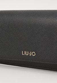 Svart teksturert lommebok med en gull "LIU·JO"-logo. Har en glatt overflate og glidelås, som fremhever et slankt og minimalistisk design.