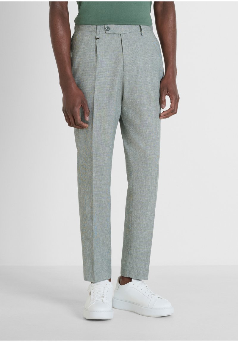 Pantaloni grigi a quadretti con vestibilità su misura, caratterizzati da un davanti doppiamente piegato, bottone in vita e gambe slim abbinate a sneakers bianche.