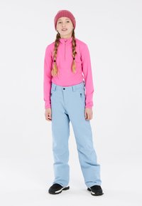 Camiseta de manga larga rosa con media cremallera, combinada con pantalones de nieve azul claro. Botas de invierno negras, gorro de lana rosa. Diseño sencillo, estilo ajustado.