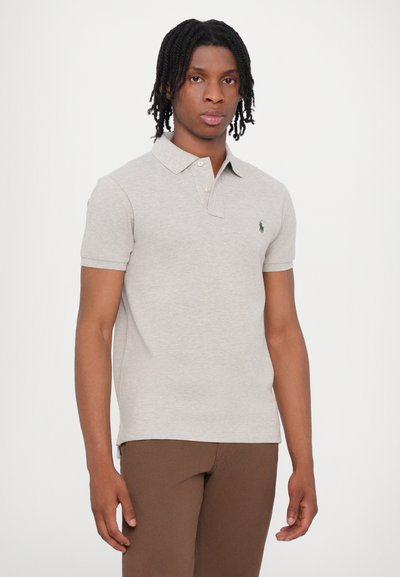 Polo shirt gri deschis dintr-un material moale, având un guler clasic, mâneci scurte și un accent cu logo verde pe piept. Design ajustat.