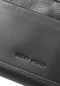 Zwarte leren portemonnee met gestructureerde accenten en gladde panelen. Voorzien van een geperst "GERRY WEBER" logo. Eenvoudig en minimalistisch ontwerp.