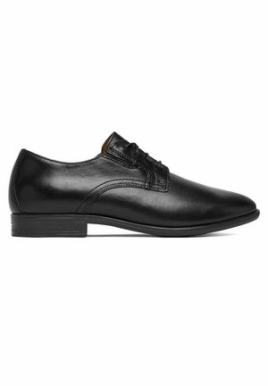 Zapato de vestir para hombre de cuero negro con cordones, tacón bajo, punta puntiaguda y costuras visibles a lo largo de los lados y la parte trasera.