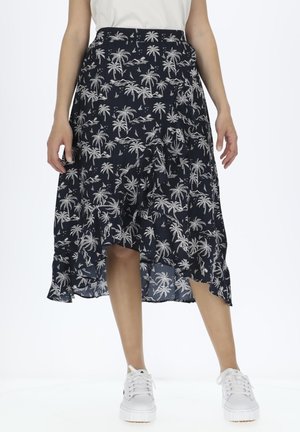 Jupe bleu marine avec un motif de palmiers blancs, ourlet volanté et coupe décontractée. Associée à des baskets blanches. Fabriquée en tissu léger.