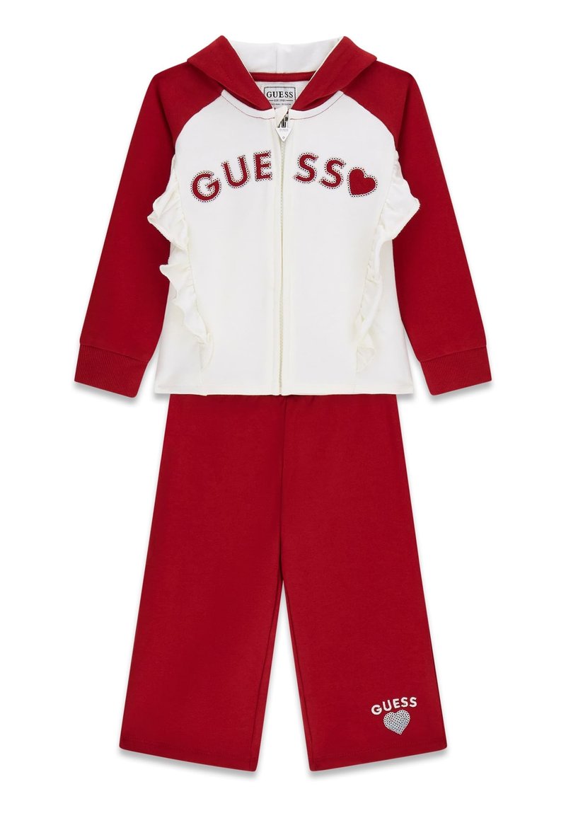 Roter und weißer zweiteiliger Trainingsanzug mit Reißverschluss-Hoodie, Rüschendetails und "GUESS"-Logo aus Strasssteinen, kombiniert mit passenden roten Hosen.