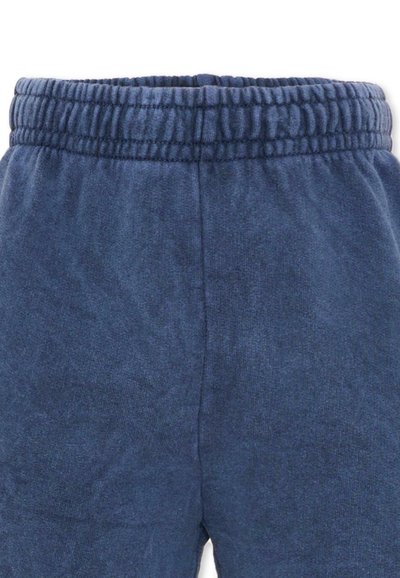 Pantalon de survêtement à taille élastique bleu foncé avec tissu doux et couture visible au centre avant.