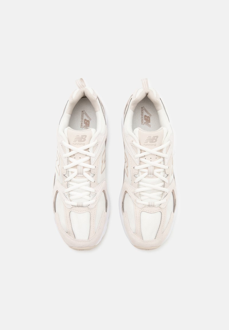 Sneakers atletici bianchi realizzati con materiali in rete e camoscio, punta tonda, lacci sul davanti e accenti neutri. Presentano il logo sulla linguetta e sul lato.