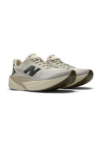Kreemjad Beisi New Balance jooksutossud musta "N" logoga ja paksude pehmendustega tallaga valgel taustal.