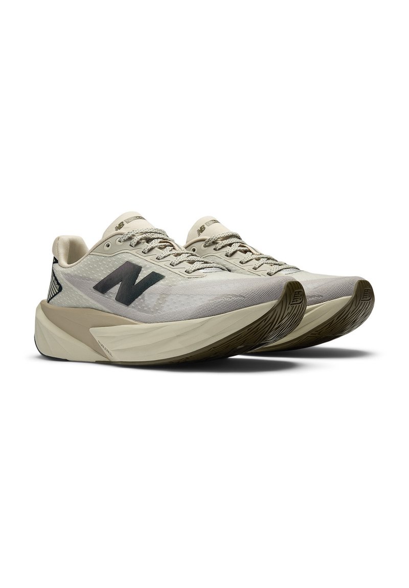 Een paar beige New Balance hardloopschoenen met een zwart "N" logo en dikke, gevoerde zolen op een witte achtergrond.