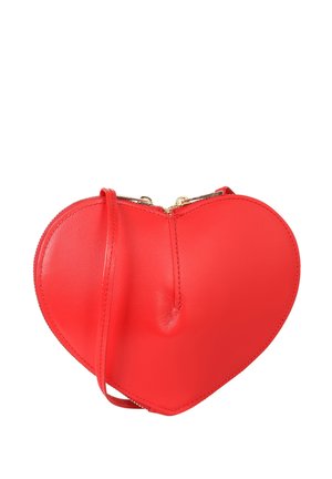 Sac bandoulière en cuir rouge en forme de cœur avec fermeture éclair dorée et fine sangle réglable sur fond blanc.