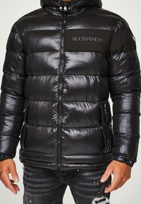 Sort puffert jakke med vandret quiltet design, hætte, frontlynlås og logo-detalje. Har en glat, skinnende tekstur og sidelommer.