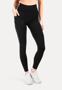 Leggings negros con cintura alta, que cuentan con un bolsillo lateral, fabricados con un tejido elástico, de textura suave y diseño ajustado.