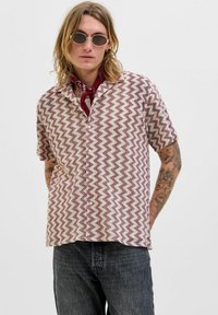Camicetta a maniche corte con motivo a zigzag in bordeaux e crema, realizzata in tessuto leggero con vestibilità comoda e chiusura a bottoni.