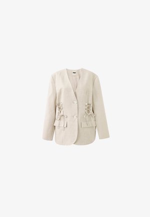 Blazer beige entallado con escote en V, dos botones delanteros, detalles de cordones y bolsillos con solapa sobre fondo blanco.