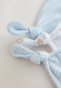 Two baby hats in light blue fabric, one with a teddy bear pattern and the other in a solid color, both featuring twisted knot tops.