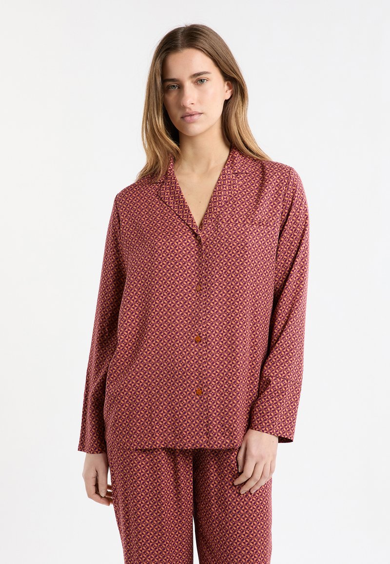 Conjunto de pijama que incluye una camiseta burdeos con patrón, cuello y cierre de botones, combinada con pantalones a juego. Tejido suave, diseño geométrico.