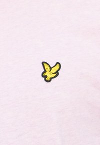 Tricou din țesătură roz deschis, cu un mic design brodat reprezentând o pasăre galbenă conturată în negru. Textură netedă, stil simplu și casual.