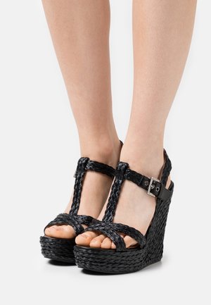 Zwarte wedge sandalen met geweven bovenste banden, T-vormig ontwerp en een enkelgesp. De plateauzool heeft een textuur van gevlochten materiaal.