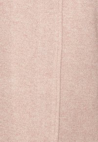 Tessuto lavorato a maglia rosa chiaro con una morbida consistenza e un sottile motivo mélange. Presenta una finitura pulita e liscia senza hardware visibile.