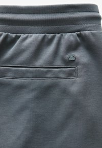 Ciemnoszare szorty sportowe o teksturowanym wykończeniu, z elastycznym paskiem, małą kieszonką i metką z logo z tyłu.