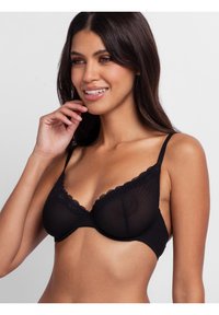 Black lace-trimmed bra with semi-sheer fabric, underwire support, adjustable straps, and a patterned texture.