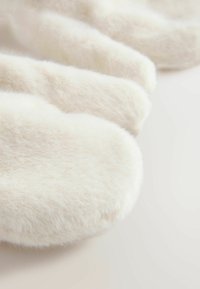 Witte, pluizige slippers met een zachte textuur en ronde vorm. Het oppervlak lijkt rijk en glad, wat comfort en warmte benadrukt.