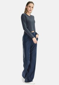 Navy long-sleeve crop top with a round neckline paired with wide-leg pants featuring side pockets. Smooth, lightweight fabric texture.
