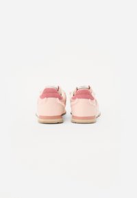 Rosa treningesko med overdel i semsket skinn og mesh, med en kontrasterende rosa hæltab, beige mellomsåle og gummisåle.