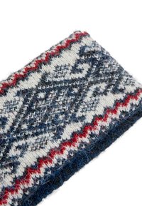 Neulekangas, jossa on geometrinen kuvio valkoisena, sinisenä ja punaisena. Poimupintainen pinta, jossa korostuvat kuidun lenkit ja tiheä kangasrakenteinen kudonta.