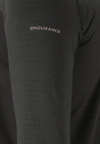Svarta atletiska leggings med ett texturerat mönster, med en silverfärgad "ENDURANCE"-logotyp på låret. Slät, åtsittande design.