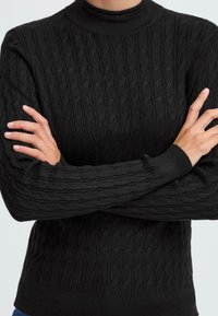 Schwarzer gestrickter Pullover mit hohem Kragen, strukturiertem Zopfmuster und gerippten Bündchen und Saum. Glattes Material mit figurbetonter Silhouette.