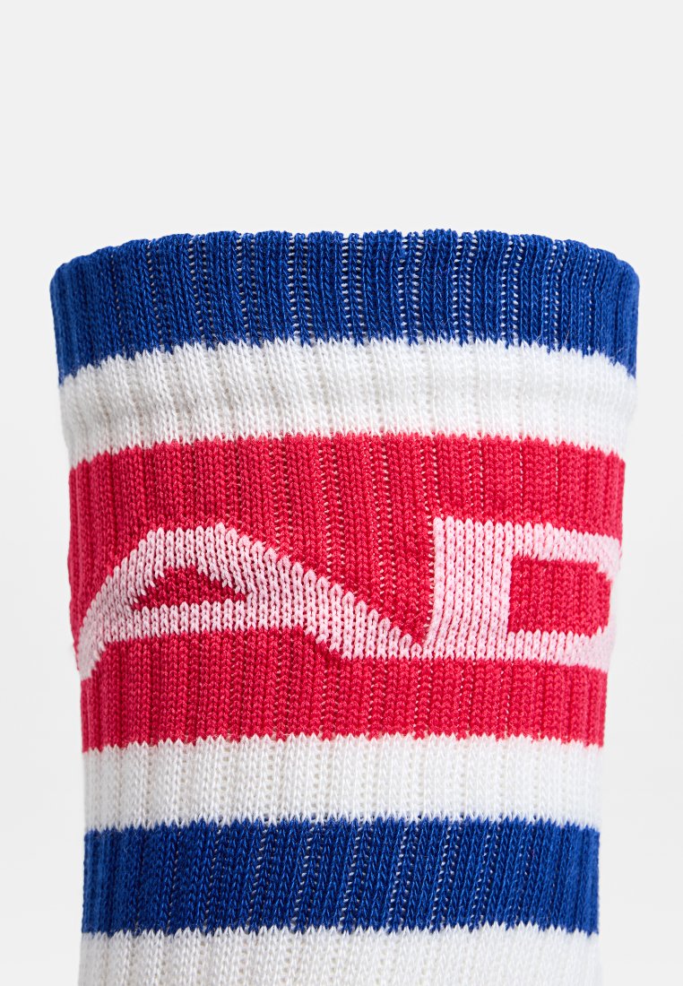 Stickad tyg med blå, vit och röd horisontella ränder som har en delvis vit stiliserad bokstavsdesign.