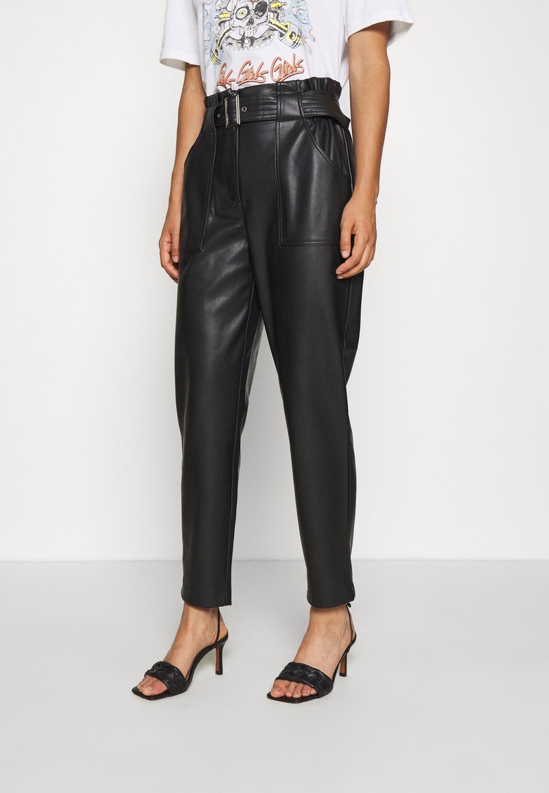 Svarta läderbyxor med hög midja som har ett bälte, frontfickor och tapered ben, i kombination med svarta klacksandaler med öppen tå.