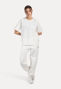 Biała bawełniana koszulka z krótkim rękawem i okrągłym dekoltem, zestawiona z białymi spodniami dresowymi o luźnym kroju i subtelnym logo.