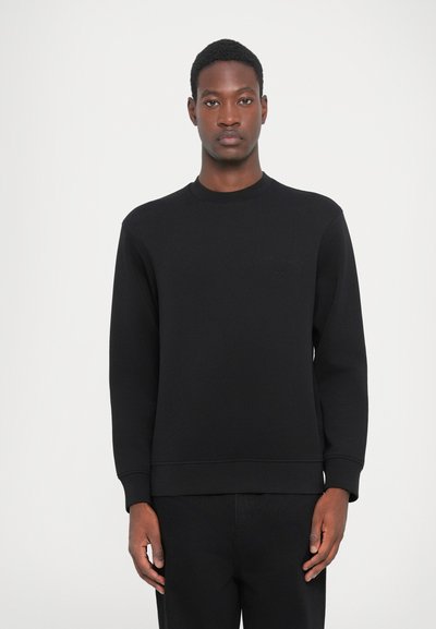 Svart sweatshirt med rund halsringning, långa ärmar och ribbade manschetter. Tillverkad av mjukt material med en subtil präglad logotyp på bröstet.