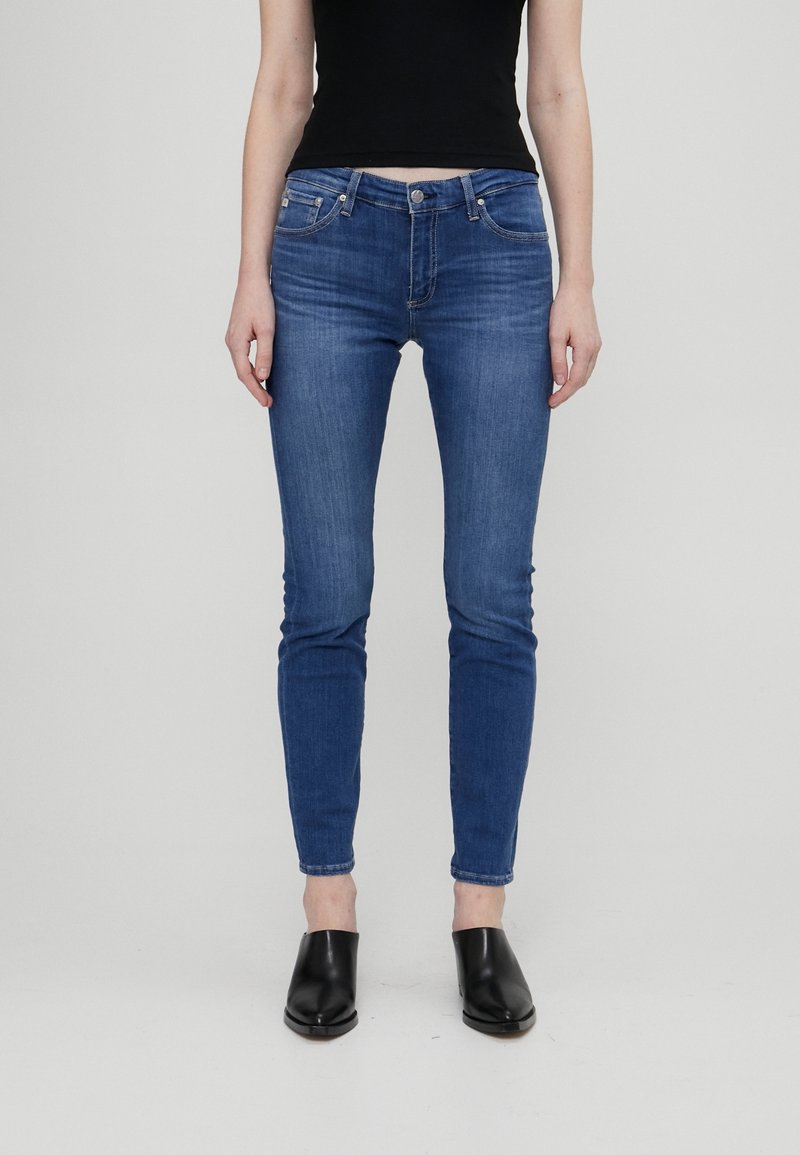 Slim-fit blå denimjeans med fem fickor, bältesöglor och dragkedja. Tyget har en lätt textur med blekning över låren.