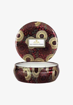 Rund Voluspa Goji Tarocco Orange duftlys i dekorativ rød, guldfarvet og brun blomsterdekoreret dåse med låg placeret bagved.