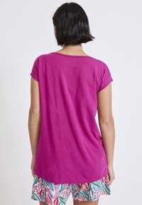 Top corto de color fucsia con mangas cortas, hecho de una tela suave y con un corte relajado, que presenta un escote redondeado y un dobladillo que llega hasta las caderas.