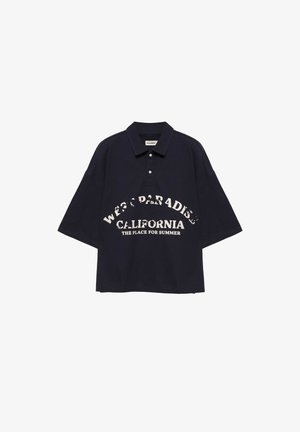 Polo noir oversize à manches courtes avec un texte blanc indiquant "West Paradise California The Place for Summer" sur le devant.