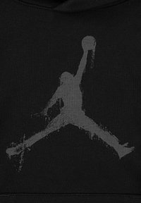 Giocatore di basket in silhouette che salta con le gambe aperte e un braccio esteso che tiene un pallone da basket, rappresentato in uno stile usurato.