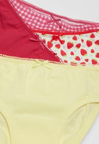 Drei Paar Unterwäsche in Rot, rosa Karomuster und Gelb, mit Ripsband-Akzenten und Spitzenbesatz. Die Innenschicht zeigt ein Erdbeer-Muster.
