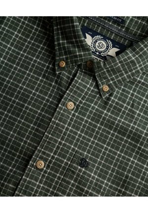Grøn ternet skjorte med hvidt rutenetmønster, der har en button-down krave, beige knapper og broderet logo på brystlommen.