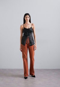 Juodas satino topas su mygtukų priekyje, derinamas su raudonais kelniais. Topas turi plonas petnešas ir atvirą nugaros detalę. Juodi aukštakulniai.