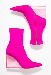 Bottines fuchsia avec une silhouette élégante et un bout pointu, fermeture éclair et un talon en coin transparent. Confectionnées dans un tissu lisse et extensible.