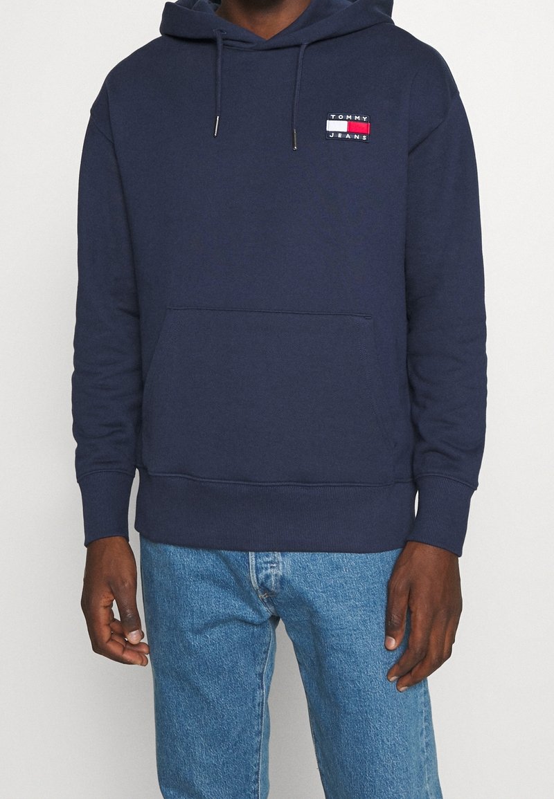 Sudadera azul marino hecha de una mezcla de algodón, con un bolsillo frontal y un parche con el logo. Tiene capucha con cordón y puños acanalados.