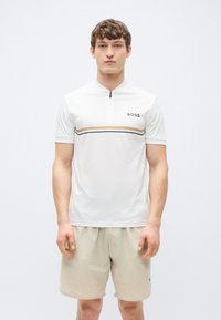 Λευκό κοντομάνικο πόλο μπλουζάκι με γιακά σε στυλ μισής φερμουάρ, με οριζόντιες ρίγες σε μπεζ και μαύρο, και μι�κρό λογότυπο «BOSS» στο στήθος.