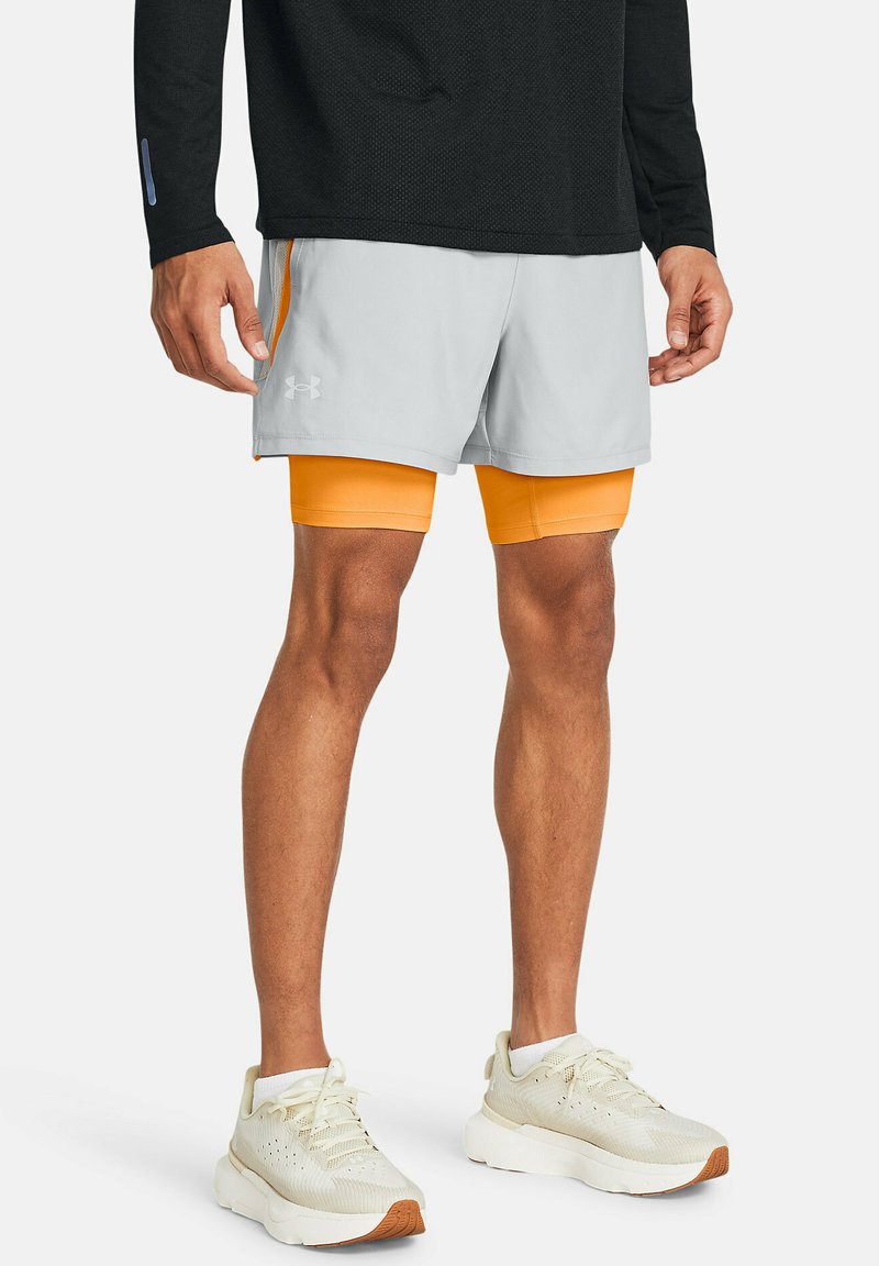 Grå sportsshorts med orange indvendig foring, båret over orange kompressionsshorts. Fodtøjet er hvidt med brune accenter. Sort langærmet trøje.